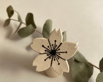 Small white and black cherry blossom brooch in glazed ceramic, shaped by hand.