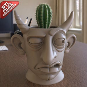 Puede incluir: Una maceta de color beige con forma de diablo con un cactus verde. La maceta tiene un ojo cerrado y un cuerno en la parte superior. La maceta está sobre una superficie de madera. La imagen incluye una pancarta de esquina roja que dice "STL FILES DIGITAL DOWNLOAD."