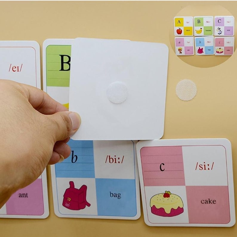 May include: A set of colourful flashcards with letters, phonetic sounds, and pictures of an ant, a bag, and a cake. The cards are designed for learning the alphabet and phonics.