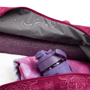 Puede incluir: Una bolsa de yoga rosa con un patr&oacute;n floral. La bolsa est&aacute; abierta y contiene una botella de agua morada y una esterilla de yoga rosa. La bolsa es resistente al agua y tiene una cremallera.