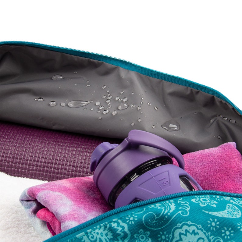 Puede incluir: Una bolsa de yoga azul turquesa con estampado paisley. La bolsa est&aacute; abierta y muestra una esterilla de yoga morada, una toalla rosa y una botella de agua morada.