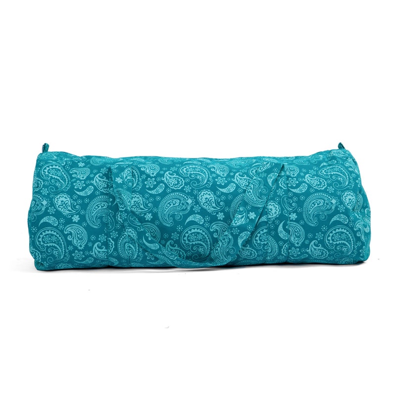 Puede incluir: Una bolsa de yoga de color azul turquesa con un patr&oacute;n de paisley. La bolsa tiene una cremallera y una correa de transporte.