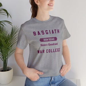 May include: A heather grey t-shirt with a purple graphic that reads "Basgiath Iron Squad Riders Quadrant War College".