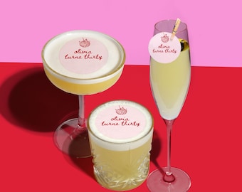 Puede incluir: Tres cócteles se muestran sobre un fondo rojo y rosa. Las bebidas están en una copa coupé, un vaso de whisky y una flauta de champán. Cada bebida tiene un círculo rosa con el texto "olivia turns thirty".