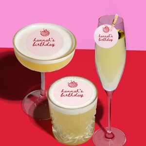 May include: Three cocktails on a red and pink background. One is in a coupe glass, one in a rocks glass, and one in a champagne flute. Each drink has a pink circle with the text "hannah's birthday".