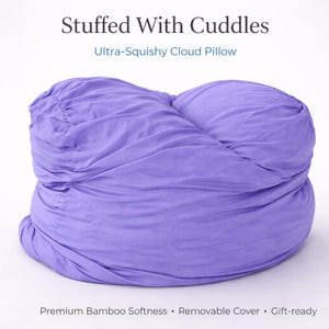 May include: A bright purple cloud-shaped pillow with a gathered, textured fabric surface. The text above reads Stuffed With Cuddles and Ultra-Squishy Cloud Pillow. Below, the text reads Premium Bamboo Softness, Removable Cover, Gift-ready.