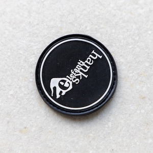 May include: Black round camera lens cap with white text that reads "Squirrels" and "Elefanti" with a stylized elephant graphic.