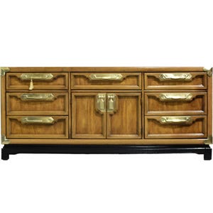 May include: A wooden dresser with brass hardware and black legs. The dresser has six drawers and two doors with brass handles.