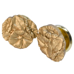 May include: A pair of gold-colored flower-shaped ear gauges. The gauges are made of a smooth, textured material and have a detailed floral design.