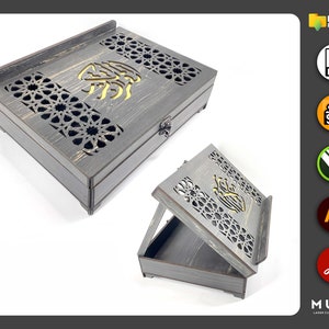 May include: A grey wooden box with intricate laser cut designs and a hinged lid. The box features a decorative Arabic calligraphy inscription and a small latch.