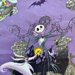 May include: A purple fabric with a black and white illustration of Jack Skellington from The Nightmare Before Christmas. Jack is standing on a stone structure with a white ghost figure in the foreground. The background includes a black bat silhouette.