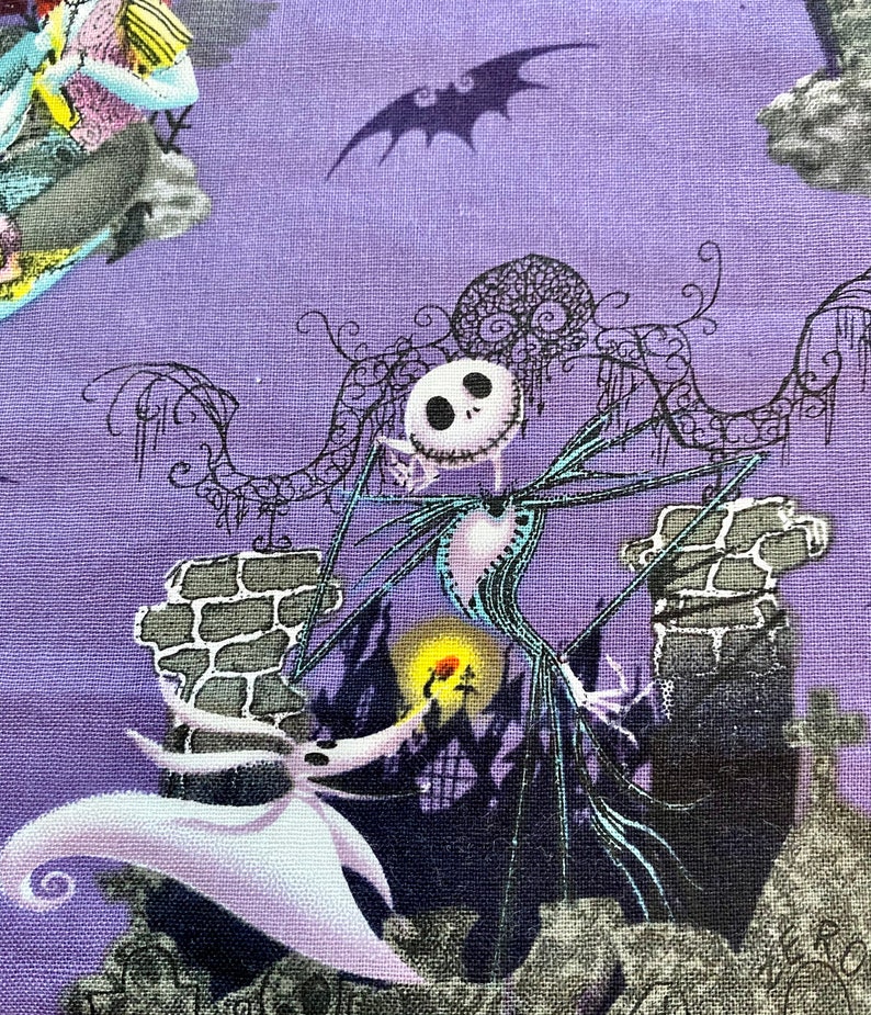 May include: A purple fabric with a black and white illustration of Jack Skellington from The Nightmare Before Christmas. Jack is standing on a stone structure with a white ghost figure in the foreground. The background includes a black bat silhouette.