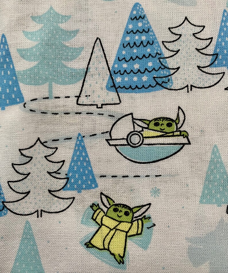 May include: A white fabric with a repeating pattern of blue and green Christmas trees and a green character from the Star Wars franchise. The character is wearing a brown robe and is flying in a spaceship. The character is also standing on the ground.