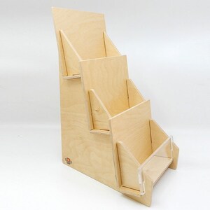 Angled front view of a wooden countertop display stand with three tiers for cards, brochures or pamphlets. The stand is made of natural wood and has a clear acrylic front panel on the bottom tier.