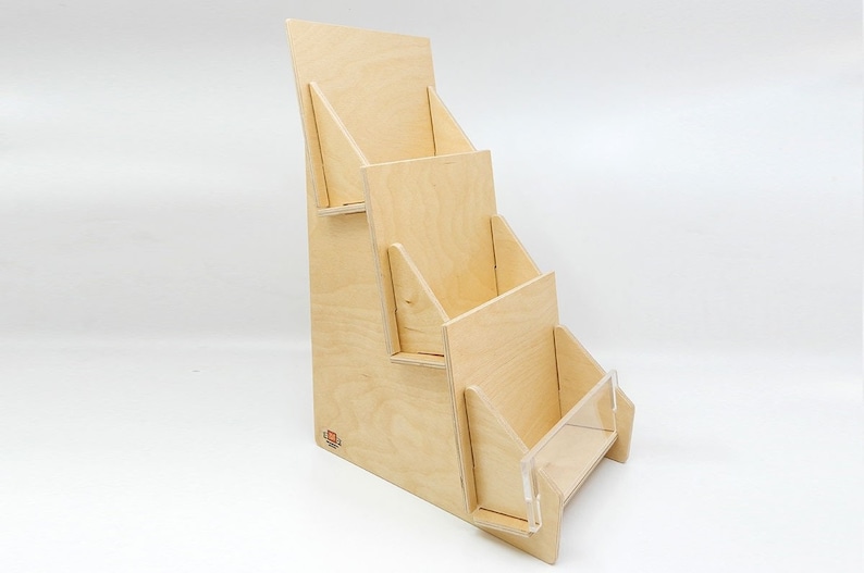 Angled front view of a wooden countertop display stand with three tiers for cards, brochures or pamphlets. The stand is made of natural wood and has a clear acrylic front panel on the bottom tier.