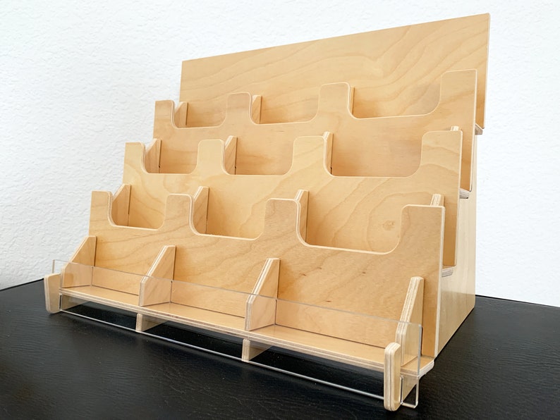 A wooden countertop display stand with 12 pockets on multiple tiers for holding stickers, small cards or brochures. The stand is made of light birch wood and has a clear acrylic front.