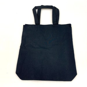 Könnte beinhalten: Eine schwarze Tragetasche mit zwei Henkeln. Die Tasche ist aus robustem Stoff und hat ein schlichtes Design.