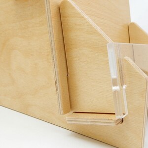 A wooden countertop display stand with a clear acrylic front. The stand has a simple design and is made of natural hue birch wood.