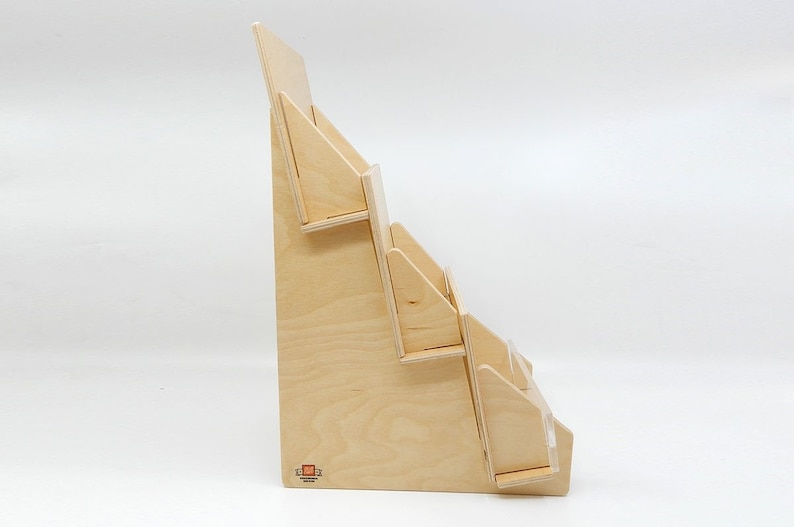 A wooden display stand with four tiers for holding cards, brochures or pamphlets. The stand is made of natural wood and has a simple, modern design. There is a clubcard logo on the bottom corner.
