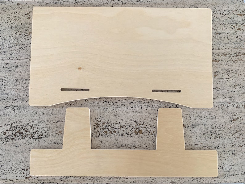 Side-angle view of a natural birch plywood 18-inch book display stand holding an open, multi-page catalog on a wooden table against a white background.