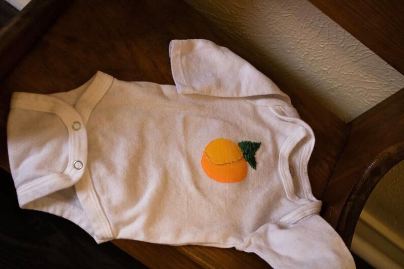 Newborn white onesie hand painted and embroidered peach