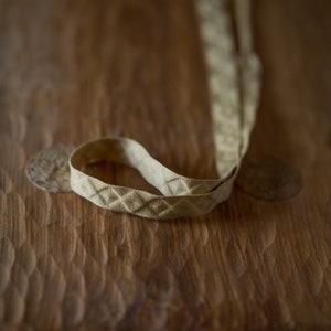 Puede incluir: Una cinta beige con un patr&oacute;n de diamantes sobre una superficie de madera.