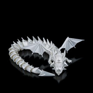 May include: A white, geometric dragon sculpture with a detailed, angular design. The dragon has outstretched wings and a long, segmented tail. The sculpture is set against a black background, highlighting its form.
