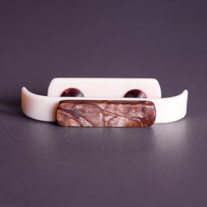 May include: Two white plastic drawer pulls with a brown marbled centre piece.