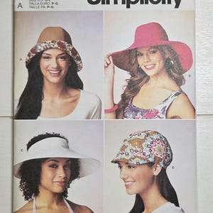 May include: Simplicity S9505 sewing pattern envelope featuring four hat styles: a tan bucket hat with a floral brim, a wide-brimmed pink hat, a white sun visor, and a patterned cap with a short brim. The text S9505 and Simplicity are printed.