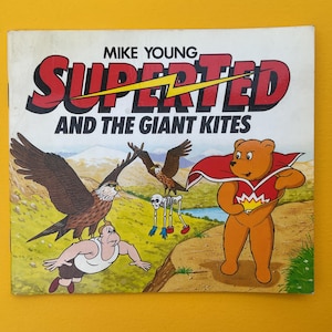 May include: A comic book cover featuring a red, yellow, and black illustration of a superhero named "Superted" and the text "Mike Young Superted and the Giant Kites".