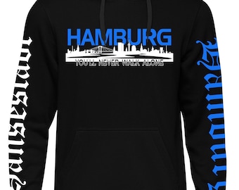 May include: Black hooded sweatshirt with the word "HAMBURG" in blue block letters above a white skyline graphic. The text "YOU'LL NEVER WALK ALONE" is below the skyline. The sleeves have white and blue text.
