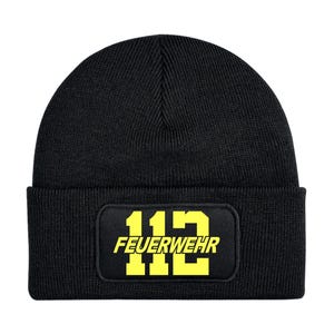 Puede incluir: Gorro negro con un parche rectangular que muestra el número "112" y la palabra "FEUERWEHR" en amarillo. El gorro es de punto y tiene un borde doblado. El texto está en negrita, en una fuente sans-serif.