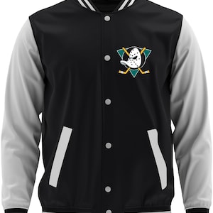 Op de afbeelding: Zwart en grijs varsity jack met witte accenten. Voorzien van een knoopsluiting, witte strepen op de manchetten en zoom, en een logo van een hockeymasker en gekruiste hockeysticks op de borst. De mouwen zijn grijs.