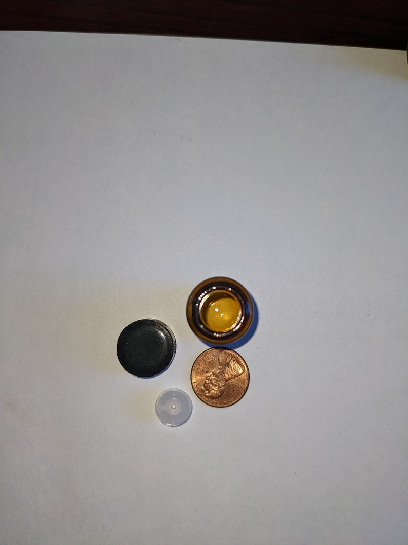 Peut inclure: Une bouteille en verre brun avec un bouchon noir et un bouchon en plastique blanc. La bouteille est &agrave; c&ocirc;t&eacute; d'un sou.