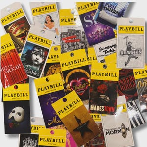 Puede incluir: Una colección de programas de teatro Playbill con varios musicales de Broadway. Los programas tienen tapas amarillas con un agujero para colgar. Los títulos incluyen "Little Shop of Horrors", "Les Miserables", "Hamilton" y "Moulin Rouge."