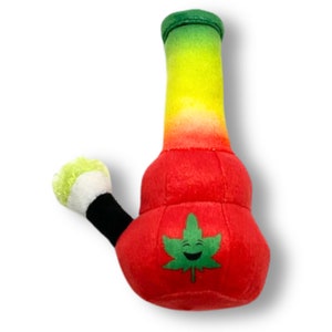 May include: A red, yellow, and green plush bong with a smiling green marijuana leaf on the front. The bong has a black and white plush mouthpiece.