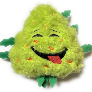 May include: A plush, lime green, smiling character with a happy face, a red tongue, and small green leaf-like appendages. The toy has orange flecks and is set against a white background.