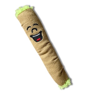 May include: A brown and tan plush toy shaped like a cigar with a green fuzzy end. The toy has a smiling face with black eyes and a red mouth.