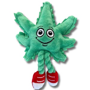 May include: Green plush toy shaped like a marijuana leaf with a smiling face and red shoes. The toy has a rope body and is designed for playing fetch.