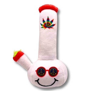 May include: White plush bong toy with a red rim and a green and yellow mouthpiece. The bong features a colorful tie-dye marijuana leaf and a smiling face with peace sign sunglasses.