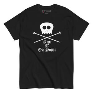 Könnte beinhalten: Schwarzes T-Shirt mit einem weißen Totenkopf- und gekreuzten Knochen-Design mit Stricknadeln. Der Text "Knit or Go Home" befindet sich darunter. Ein bequemes T-Shirt mit kurzen Ärmeln für Stricker.