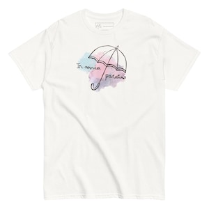 May include: Off-white t-shirt featuring a black line drawing of an umbrella with the words "In omnia paratus" in black script. The umbrella design is over a watercolor-style splash of blue and pink. The shirt has short sleeves and a crew neck.