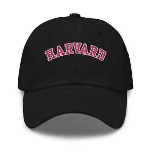 May include: Black baseball cap with a pink embroidered "HARVARD" logo.