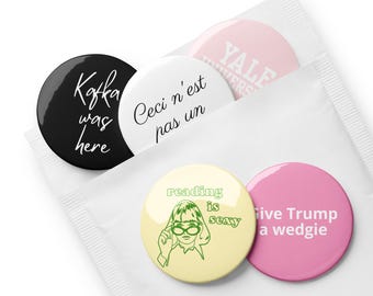 May include: Five round button pins with various designs and text. The pins are in a white plastic bag. The text on the pins includes "Kafka was here", "Ceci n'est pas un", "Yale University", "Reading is sexy", and "Live Trump a wedgie".