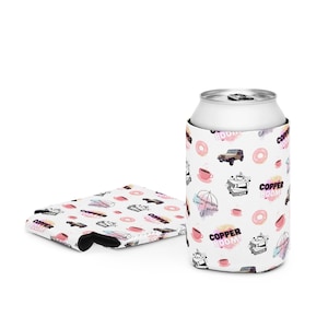 May include: White can cooler with a pink and black pattern featuring doughnuts, coffee cups, an umbrella, and the text "Copper Boom".