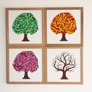 May include: A set of four square wall art prints in light wood frames, each featuring a tree with a brown trunk. The trees display distinct foliage colors: one green, one orange and yellow, one pink and purple, and one bare brown branch structure.