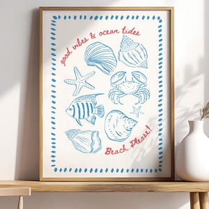 Puede incluir: Lámina enmarcada con dibujos lineales azules de conchas marinas, una estrella de mar, un cangrejo y un pez sobre un fondo crema. Las palabras "good vibes & ocean tides" y "Beach Please!" están escritas en rojo. El marco es dorado.