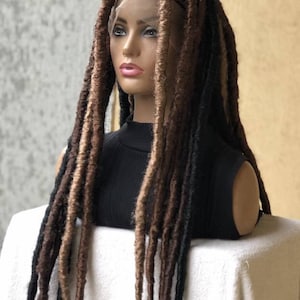 Puede incluir: Una peluca larga de rastas sintéticas de color marrón y negro con un frente de encaje. La peluca está peinada en un estilo recto y con raya.