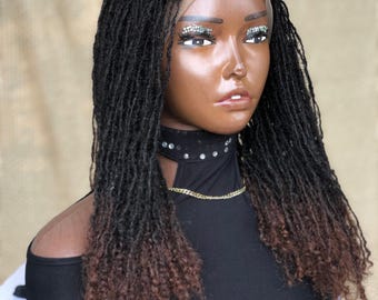 Può includere: Una parrucca sintetica con dreadlock ombré nero e marrone con un fronte in pizzo. La parrucca è acconciata con dreadlock lunghe e sciolte.
