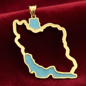 May include: A gold-colored pendant in the shape of the country of Iran, with a light blue enamel fill. The pendant is suspended from a small loop at the top. The background is a deep red velvet.